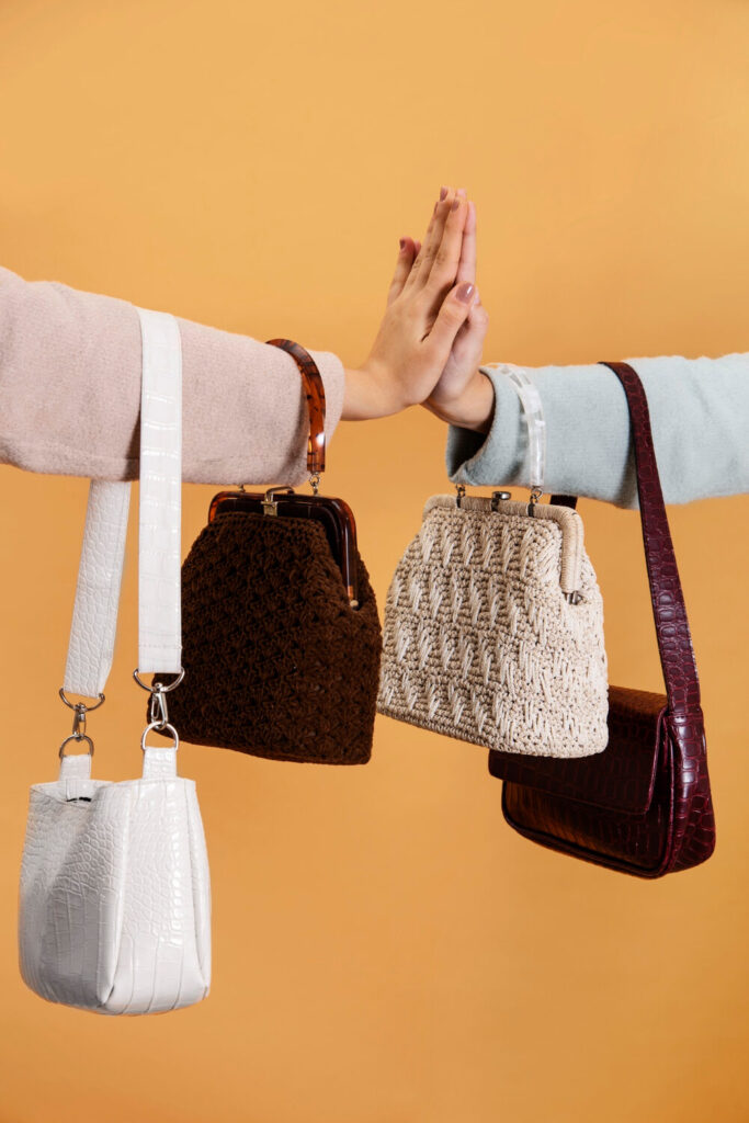 Duas amigas juntando as mãos em sinal de amizade, usando bolsas parecidas